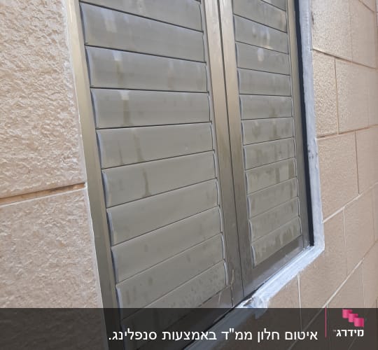 חלון אטום עם חומר איטום לבן סביב המסגרת